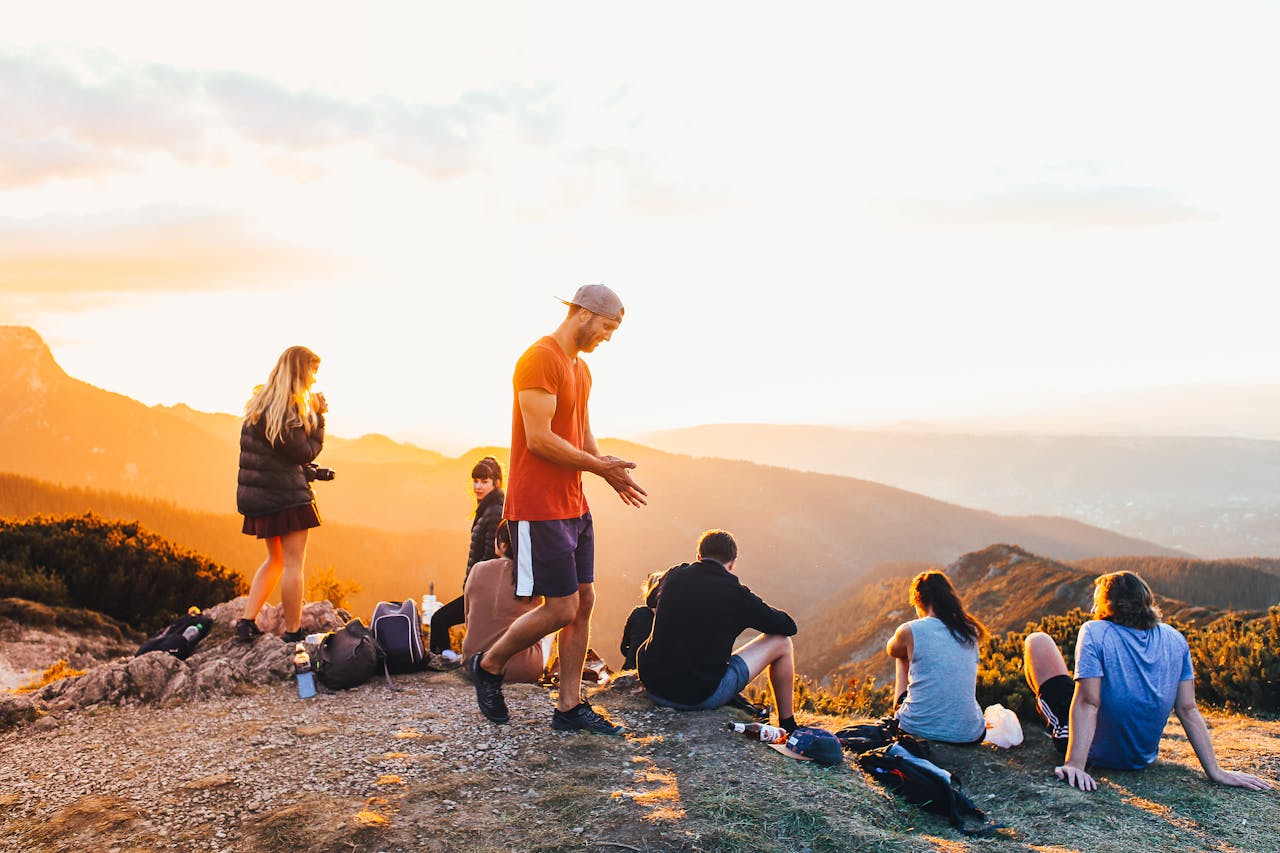 People relaxing and enjoying a sunset view on a mountain hike, capturing a tranquil outdoor moment.